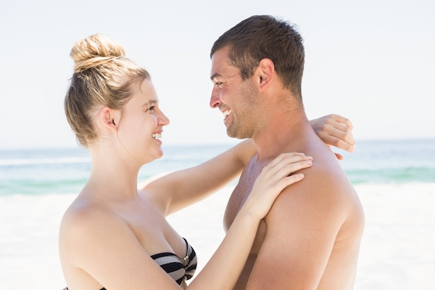 Casal sorridente, abraçando na praia