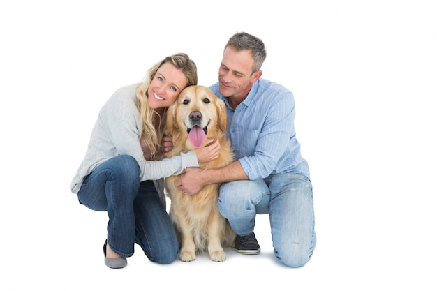 Foto casal sorridente acariciando seu golden retriever