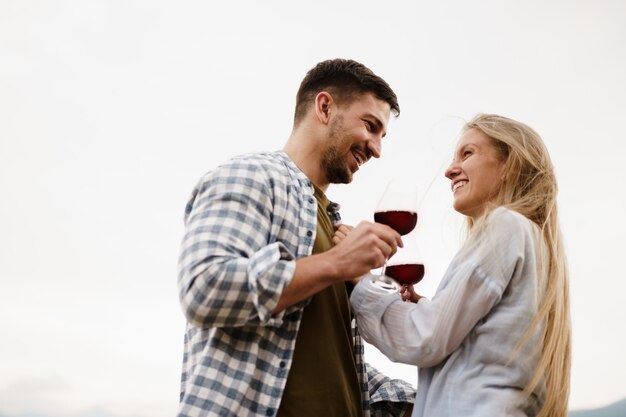 Foto casal sorridente brindando taças de vinho ao ar livre nas montanhas