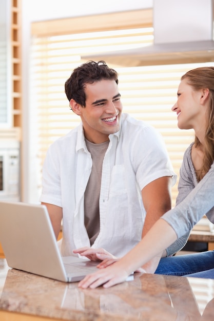 Casal sorridente com laptop na cozinha