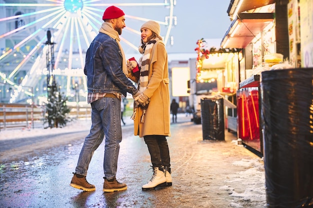 Casal sorridente comemorando o natal no parque de diversões