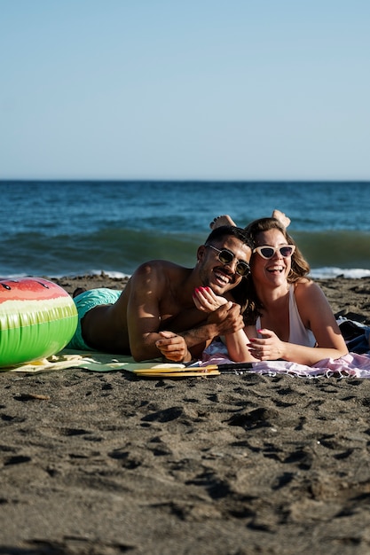 Casal sorridente de tiro completo na praia