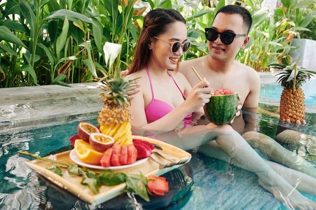 Casal sorridente descansando em uma pequena piscina