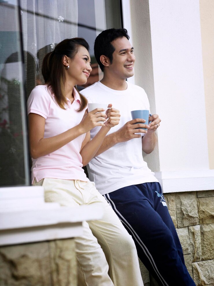 Foto casal sorridente falando enquanto toma café contra a parede