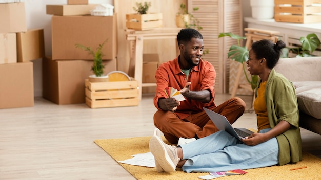 Casal sorridente fazendo planos para reformar a casa usando laptop e paleta de cores