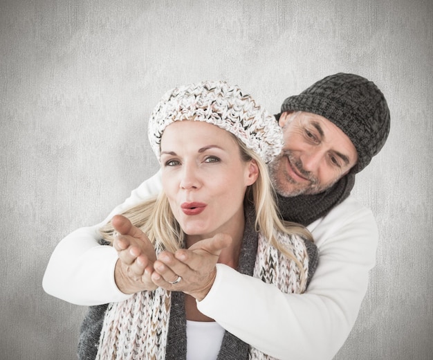 Casal sorridente na moda de inverno posando contra a superfície resistida