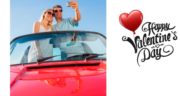 Casal sorridente parado em cabriolet vermelho tirando foto contra mensagem fofa de dia dos namorados