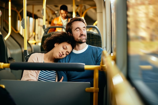 Casal sorridente relaxando com os olhos fechados enquanto viaja de ônibus
