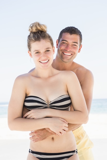 Casal sorridente se abraçando na praia