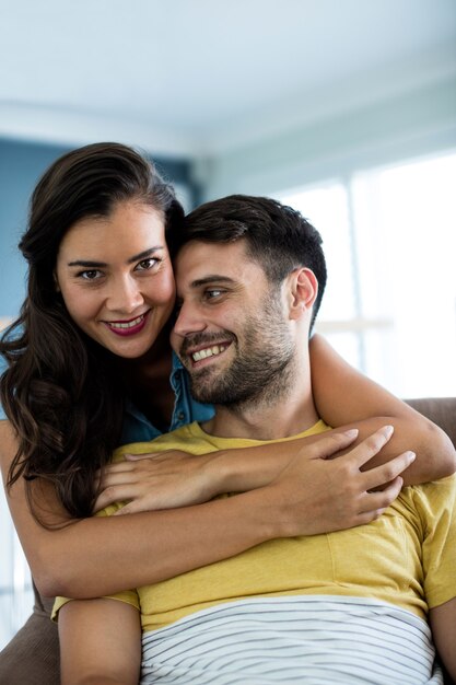 Casal sorridente se abraçando na sala de estar de casa