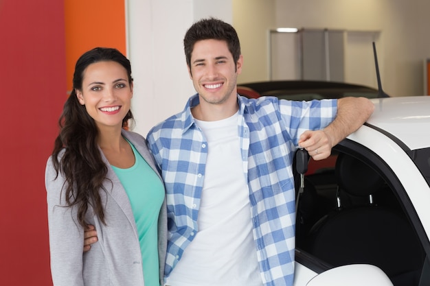 Casal sorridente segurando a chave do carro novo