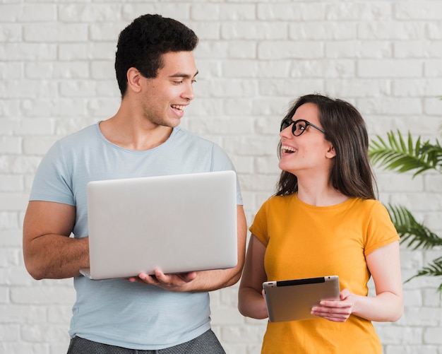 Casal sorridente usando laptop e tablet digital