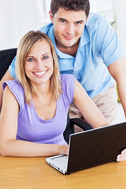 Casal sorridente usando o computador na mesa