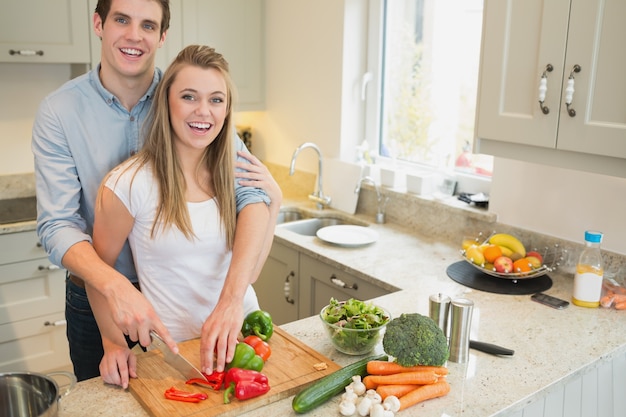 Casal sorrindo e trabalhando na cozinha