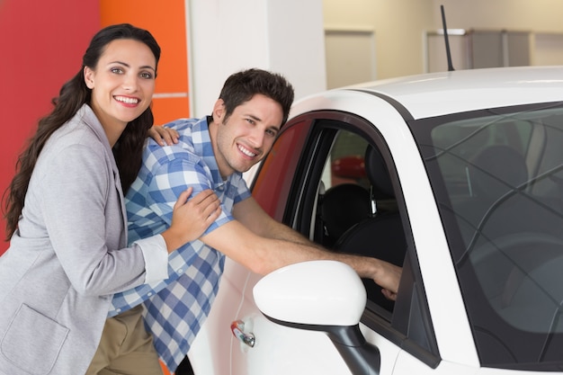 Casal sorrindo olhando dentro de um carro