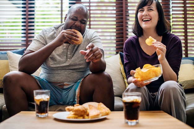 Casal tendo fast food no sofá