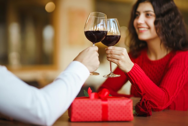 Casal tilintar copos com vinho tinto Amantes dão presentes um ao outro Adorável jantar romântico