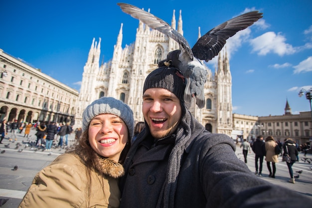 Casal tirando auto-retrato com pombo na praça duomo em milão.