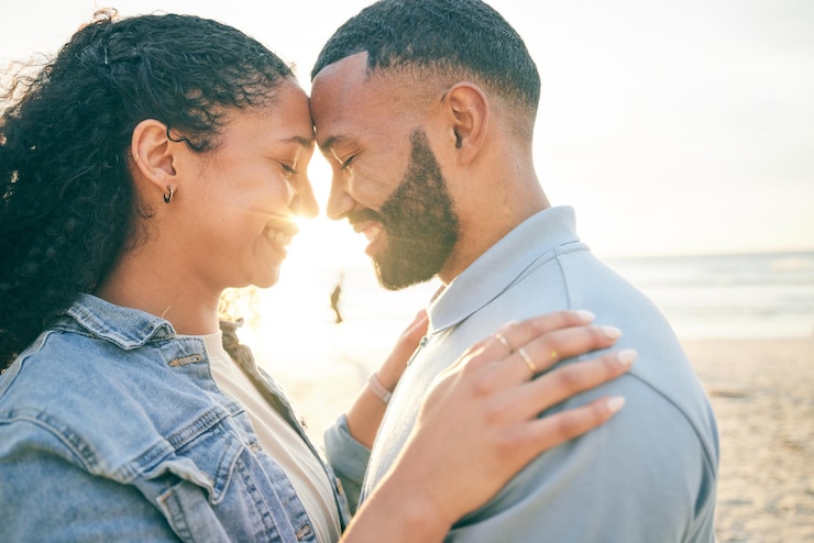 Foto casal toca na testa e abraça a praia e o oceano com vínculos de viagem e amor, confiança e casamento ao ar livre férias de aventura e sol homem e mulher com lealdade e parceiro de vida na natureza