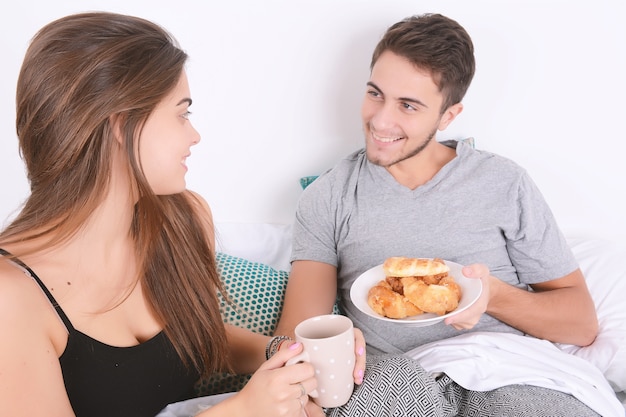 Casal tomando café da manhã na cama.