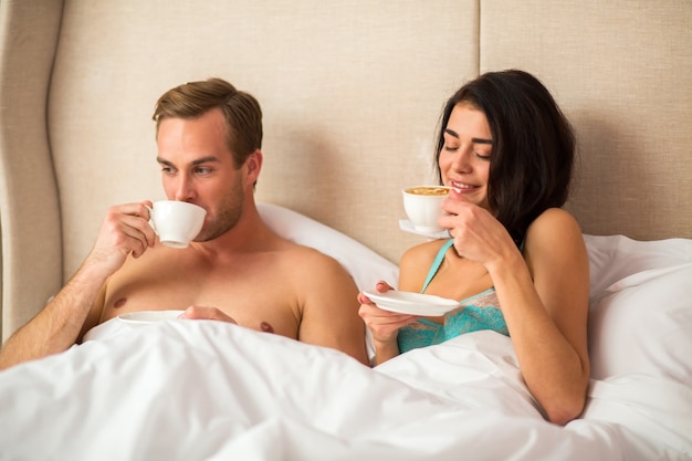 Casal tomando café na cama.