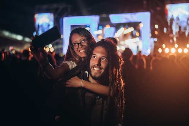 Casal tomando selfie com um smartphone em um festival de música