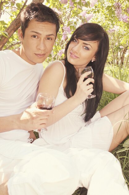 Casal tomando taças de vinho sob o arbusto lilás
