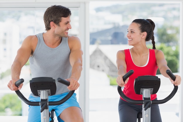 Casal trabalhando na aula de spinning no ginásio brilhante