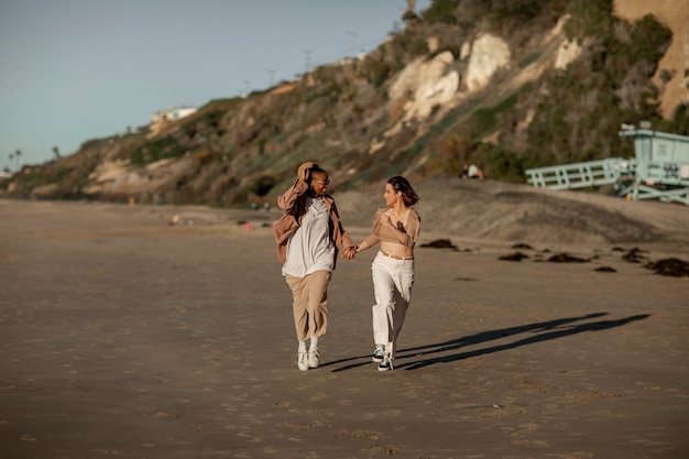 Foto casal trans correndo na praia e de mãos dadas