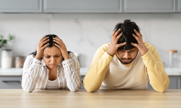 Foto casal triste com as mãos na cabeça sentado na cozinha