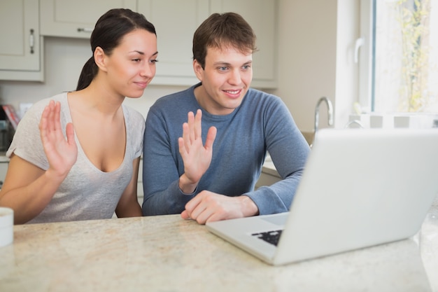 Casal usando o laptop para bate-papo por vídeo e acenando