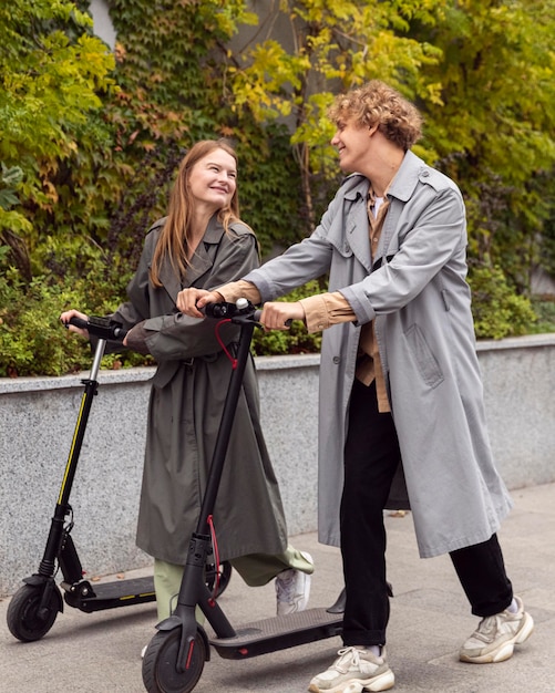 Foto casal usando scooter elétrico ao ar livre