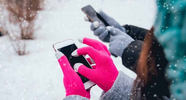 Casal usando smartphone no inverno com luvas para telas sensíveis ao toque