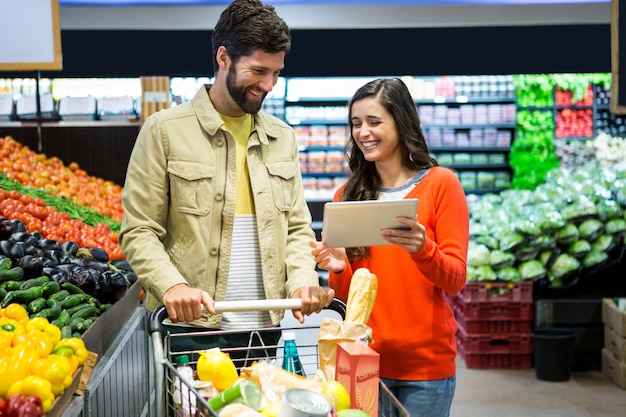 Casal usando tablet digital enquanto fazia compras