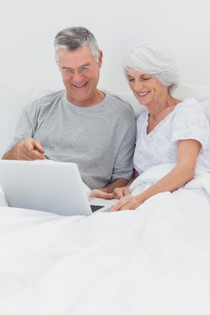 Casal usando um laptop juntos na cama