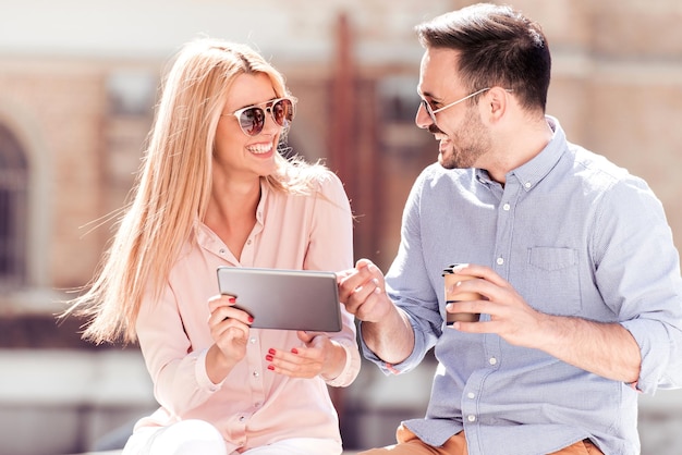 Casal usando um tablet e café para ir ao ar livre