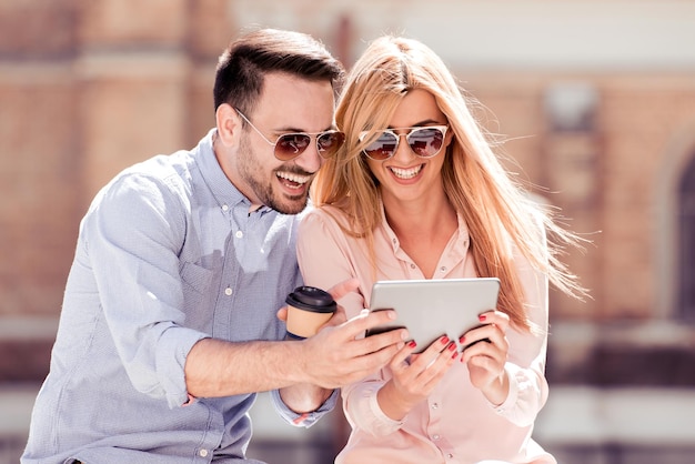 Casal usando um tablet e café para sair ao ar livre