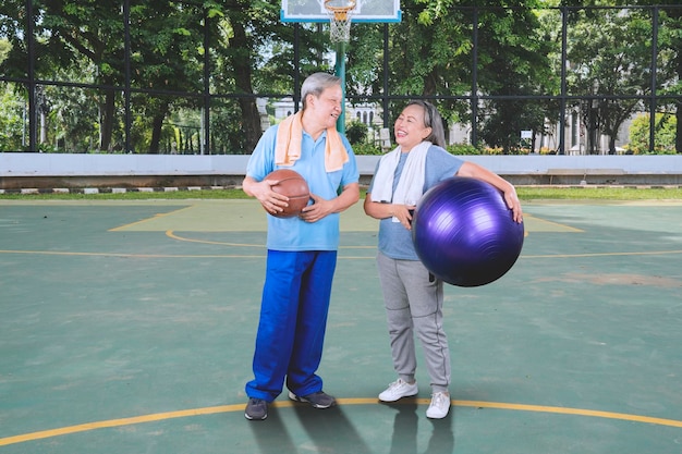 Casal velho feliz segura bola de basquete e pilates