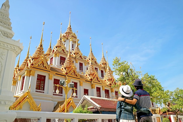 Casal visitando o lindo pagode loha prasat adornado com 37 torres douradas em bangkok tailândia