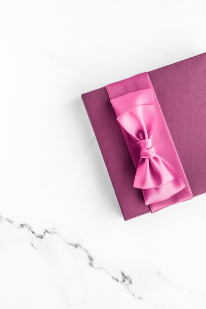 Casamento de aniversário e conceito de marca feminina caixa de presente rosa com laço de seda no fundo de mármore presente de chá de bebê para meninas e presente de moda glamour para design de arte plana de luxo para marcas de beleza