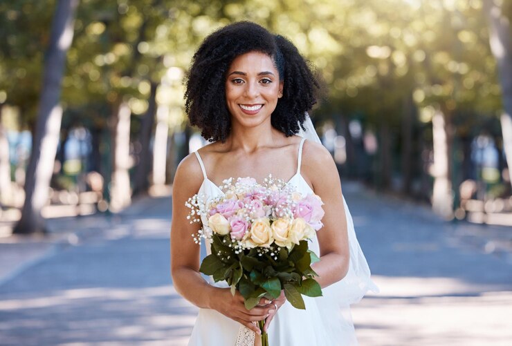 Foto casamento de mulher negra e retrato de noiva com buquê de rosas feliz com a celebração do amor felicidade de rua e flores de um jovem sorriem no evento de compromisso de casamento sorrindo ao ar livre