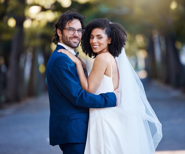 Casamento de retrato de casal e amor interracial ao ar livre para evento de celebração de casamento junto com cuidado Homem e mulher casados felizes no parque com parceria de confiança e abraço para felicidade e segurança