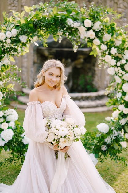 Casamento em uma antiga vila vinícola na Toscana, Itália. Retrato de uma noiva perto de um arco redondo de flores. O cenário para a cerimônia de casamento.