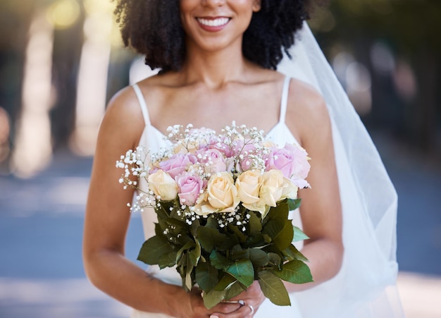 Casamento feliz e sorriso com noiva e flores para celebração de beleza e evento de primavera Felicidade maquiagem e moda com mulher negra e buquê de rosas para festa de casamento e cerimônia ao ar livre