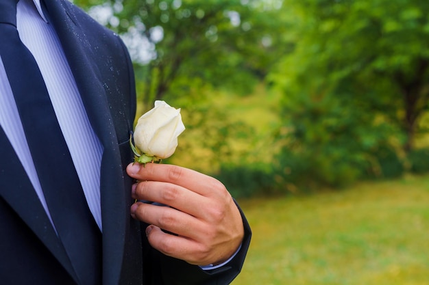 Casamento o noivo de camisa e colete com casa de botão está no jardim