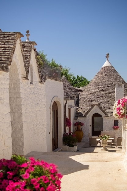 Casas com telhado de cone paredes brancas com cal e pedra no telhado vasos de flores e plantas céu claro harmonia e simplicidade