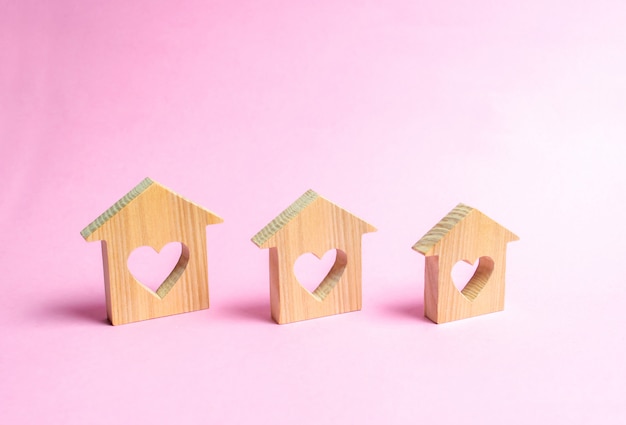 Casas con corazones en el interior sobre un fondo rosa.