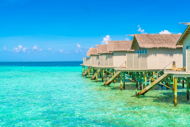 Casas de campo bonitas da água na ilha tropical de Maldivas.
