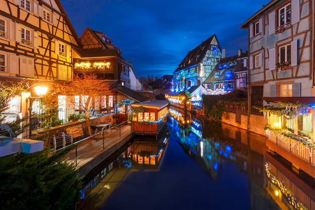 Casas de enxaimel tradicionais da Alsácia e o rio Lauch em Petite Venise ou na pequena Veneza, cidade velha de Colmar, decoradas e iluminadas na época do Natal, Alsácia, França