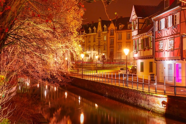 Casas de enxaimel tradicionais da Alsácia em Petite Venise ou na pequena Veneza, cidade velha de Colmar, decoradas e iluminadas na noite de Natal com neve, Alsácia, França